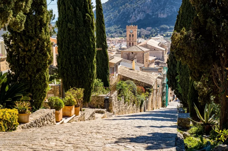Carrer del Calvari-trappen med cypres fører 365 trin ned til den gamle bydel i Pollensa med en fantastisk udsigt over hustagene til kirken Santa Maria dels Àngels og bjerget Puig de Maria.